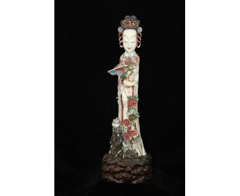 A Chinese polychrome coloured ivory figure of Guan Yin, carved in high relief, c1900, standing holding an Oriental pheasant b