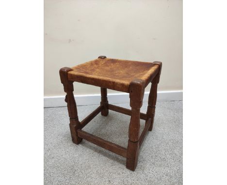 Robert "Mouseman" Thompson, oak stool with rectangular hide top on faceted turned support with understretcher, 39cm x 36cm.&n