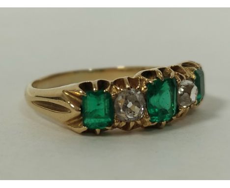 Edwardian half hoop style ring with three emeralds and two old cut diamond brilliants, probably 18ct gold, size 'P½'.Conditio