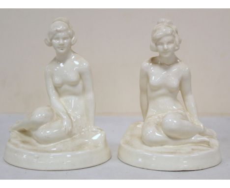 A pair of Royal Worcester white porcelain Art Deco style figures of two seated female nudes on naturalistic circular plinth b