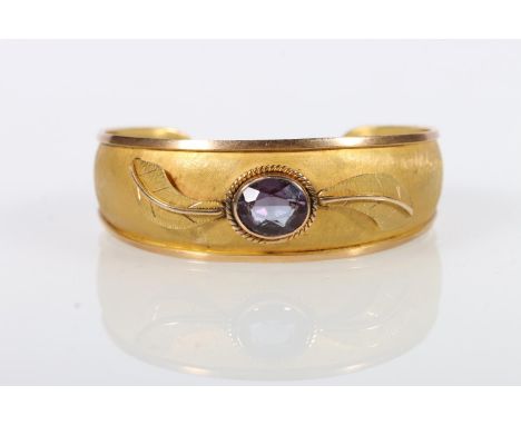 18kt yellow gold bangle set with faceted amethyst stone, the texture body with two relief leaves, 21.2g gross. 59mm wide but 