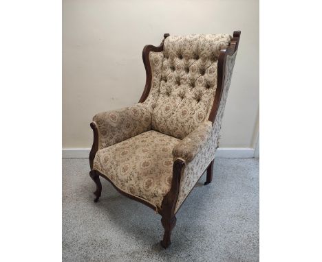 Edwardian walnut framed wing armchair with button back and show-wood side rails and arm terminals on slim cabriole supports, 