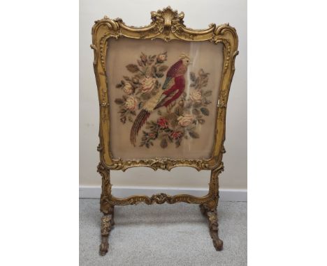 Ornate 19th century firescreen, the foliate scroll gilt frame enclosing a cushioned tapestry depiction of an exotic bird amon