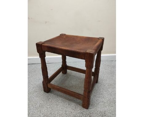 Robert "Mouseman" Thompson, oak stool with rectangular hide top on faceted turned support with understretcher, 36cm x 41cm.&n