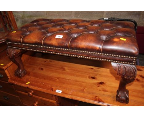 A button down leather upholstered foot stool raised on claw and ball supports