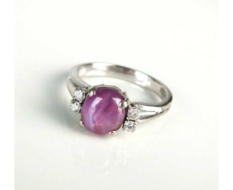 A star ruby and diamond ring, designed as a central oval cabochon star ruby flanked to each side by two brilliant cut diamond