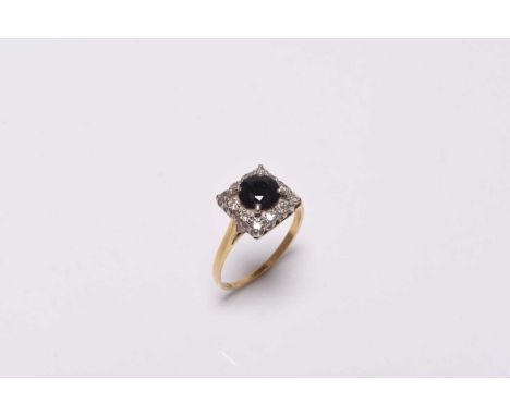 A sapphire and diamond cluster ring, designed as a central round mixed cut sapphire claw set within a square border of round 