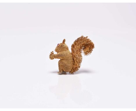 A yellow metal squirrel brooch, naturalistically modelled with faceted ruby set eyes and holding a pine cone, stamped '14k', 