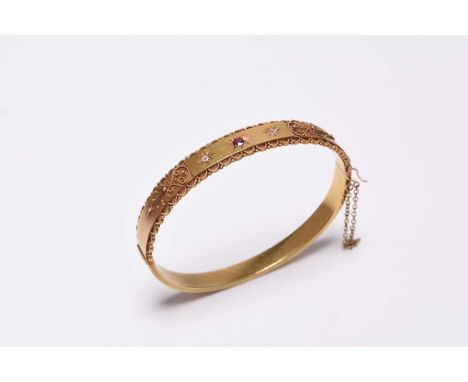 A late 19th century untested ruby and diamond hinged bangle, with applied filigree decoration, the integral push clasp stampe