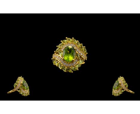 Peridot and White Zircon Cluster Ring, a 2.5ct oval cut feature peridot set, slightly raised, in the centre of the asymmetric