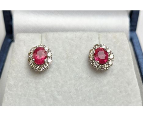 A PAIR OF 18CT WHITE GOLD RUBY AND DIAMOND STUD EARRINGS, each with a single faceted ruby of approximately 0.30 carats, surro