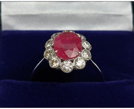 AN 18CT WHITE GOLD RUBY AND DIAMOND CLUSTER RING, the central ruby of approx. 1.87 carats, surround by ten bezel set round br