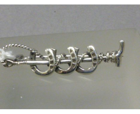 A Silver Tie Pin in the form of Three Horse Shoes and a Whip