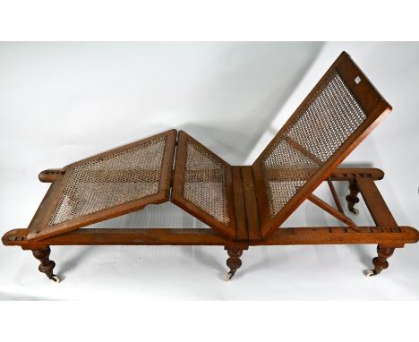 A Victorian oak framed cane panelled campaign bed, probably by Robinson, with three hinged section raised on six turned legs 