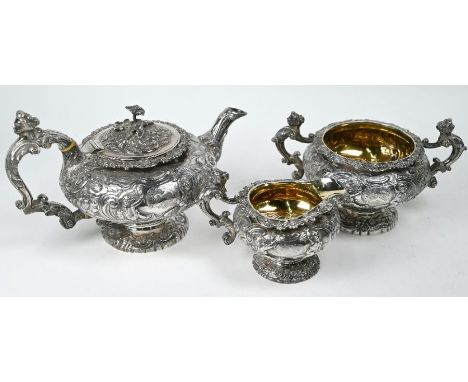 A good quality George IV silver three-piece tea service of compressed melon form on stemmed foot, richly embossed and chased 