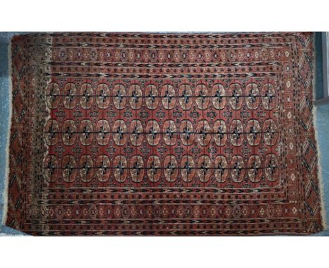An antique Turkoman rug, the pale red-brown ground with three rows of guls, 190 cm x 127 cmEven wear, both ends missing, no s