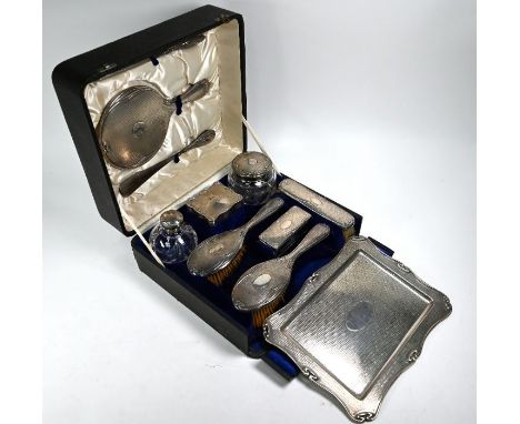 An Edwardian silver dressing table set with Art Nouveau borders and engine-turned decoration, comprising pin-tray, three brus