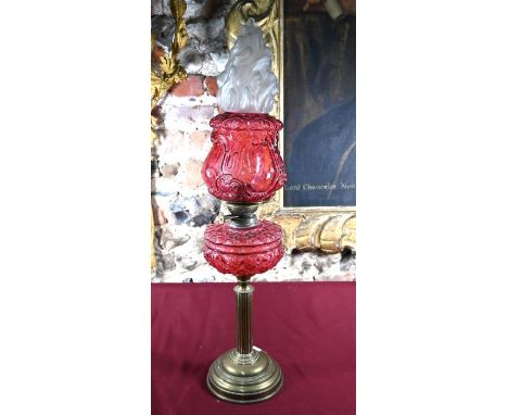 A late 19th century brass column oil lamp, with moulded cranberry glass font and shade, 77 cm hUnassociated flambeau shade ha