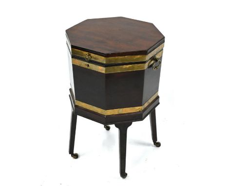 A George III brass bound mahogany wine cooler of octagonal form, raised on square tapered legs, to brass castors, with brass 