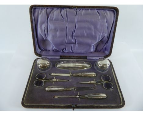 A George V Silver Manicure Set, comprising of manicure tools, two scissors, buffer and two cut glass jars, Birmingham hallmar