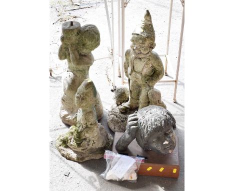 A group of concrete garden ornaments to include a large gnome and a babies head together with two iron plant stands, two conc