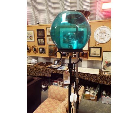 An ornate black painted wrought iron standard lamp with blue glass shade