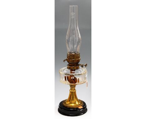An early 20th century brass pedestal oil lamp, having clear glass reservoir to brass column base (lacking shade)