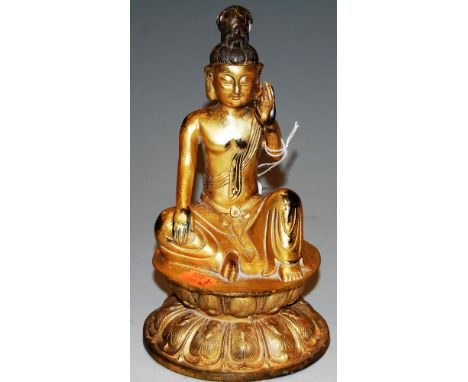 A gilt bronze figure of a Buddha in seated lotus pose with arm raised, having impressed leaf mark verso, h.24cm 