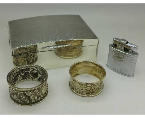 A silver cigarette box, two silver napkin rings including one Victorian decorated with grapes and a Ronson lighter