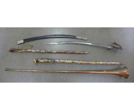 Two walking canes, each with enamel badges applied, a copper horn and an Indian sword
