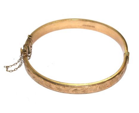 A 9 carat gold bangle with decoration to one half in relief 
