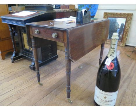 An early 19th century mahogany Pembroke table, the rectangular drop leaves over an ebony strung drawer on ring turned taperin