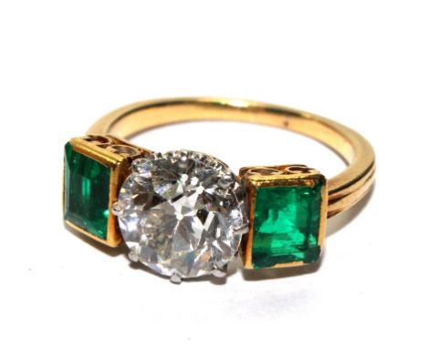 A hallmarked 18 carat gold tested emerald and diamond three stone dress ring, the old cut claw set diamond to the centre with