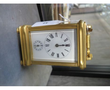 A brass carriage clock, of conventional form with enamel dial and subsidiary alarm dial, the movement striking on a bell in t