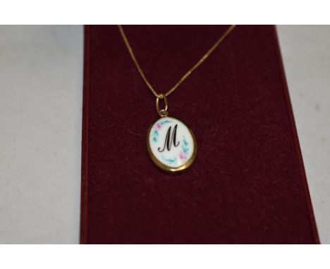 A ceramic pendant for initial M in a yellow metal mount on a 9ct gold box chain, approx 2.6g
