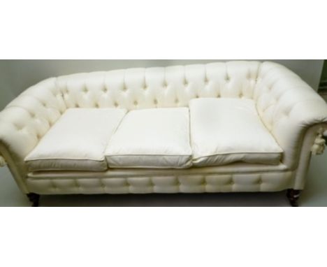 A 19TH CENTURY LOW BACKED CHESTERFIELD SOFA, currently upholstered in ivory silk, having three feather filled squab cushions,