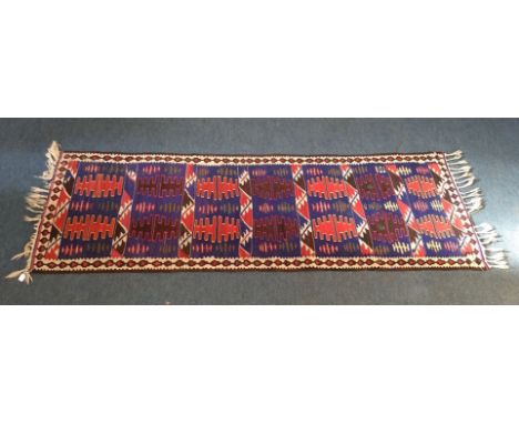 A 20th Century kilim runner, seven panels with comb decoration on blue ground, ivory border with cruciform motifs, 212 cm x 6