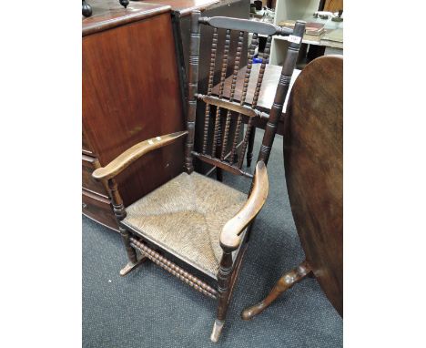 An early 19th Century elm vernacular armchair having bobbin spindle back with rush seat and bobbin frame