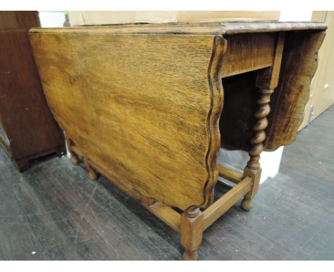 An early/mid 20th Century golden oak drop leaf  dining table having scallop edge on twist gate legs