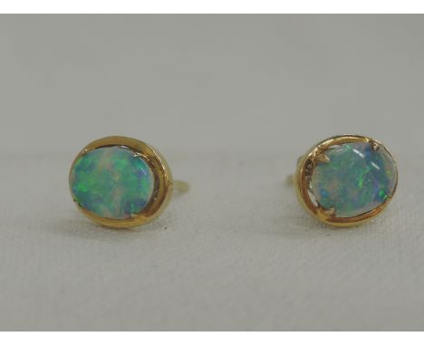 A pair of yellow metal stud earrings having oval opal panels in claw mounts