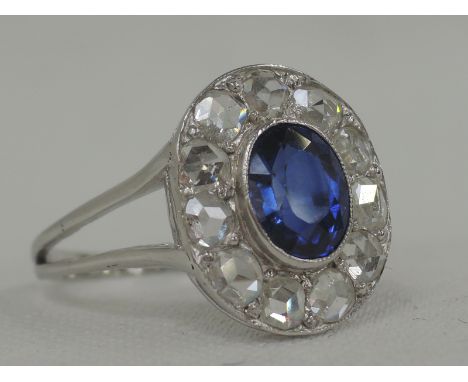 A lady's dress ring having an Art Deco style oval sapphire and old cut diamond cluster, approx 1ct diamonds on a white metal 