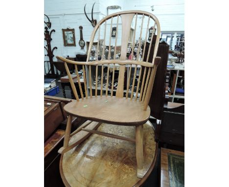 A 1960s design beech and light elm Ercol rocking armchair having comb spindle back with solid seat