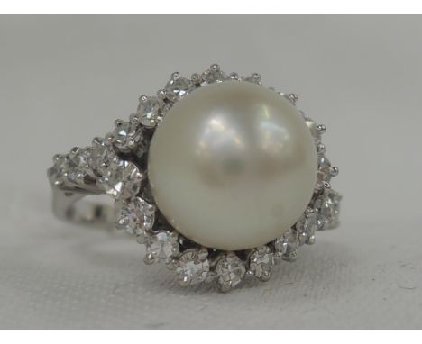 A lady's dress ring having a large central cultured pearl within a swag surround of 22 diamonds in a raised basket mount on a