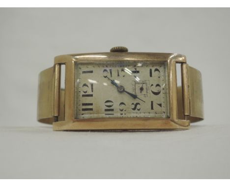 A lady's 9ct gold watch having Arabic numeraldial with subsidiary seconds to a rectangular face on a rolled gold bangle strap