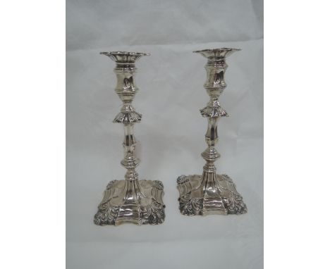 A pair of Victorian silver candlesticks having shell scroll decoration to removable sconses and weighted bases with tapered m