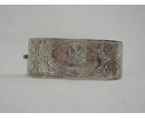 A 1930's HM silver hinged bangle having engraved pictorial decoration