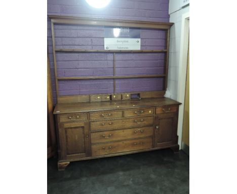 A 19th century oak dressing base having shelf Delft rack and drawers, over central drawers flanked by cupboards and drawers, 