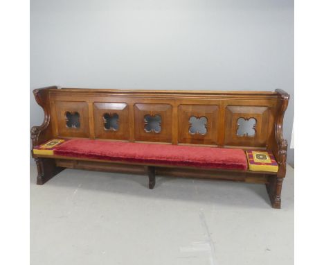 A Victorian Gothic oak church pew, with carved decoration, pierced back panels, upholstered seats cushion and two needlepoint