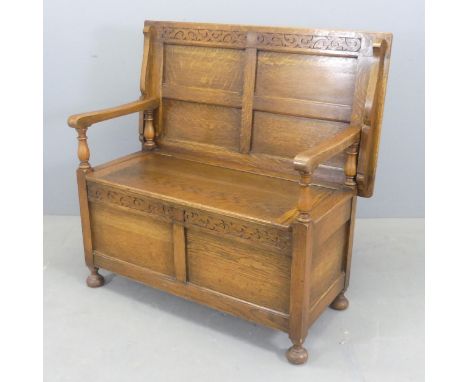 A panelled oak monk's bench, with lifting seat and carved decoration. Dimensions (as table) - length 107cm, height 74cm, widt