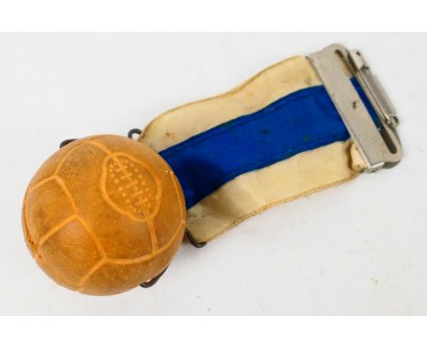 Football Item, A small rubber ball in the shape of a football with blue and white ribbon attached and a medal clasp. Possible